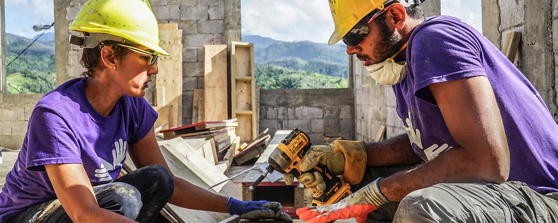 International volunteers drilling the exterior framework of a home being rebuilt