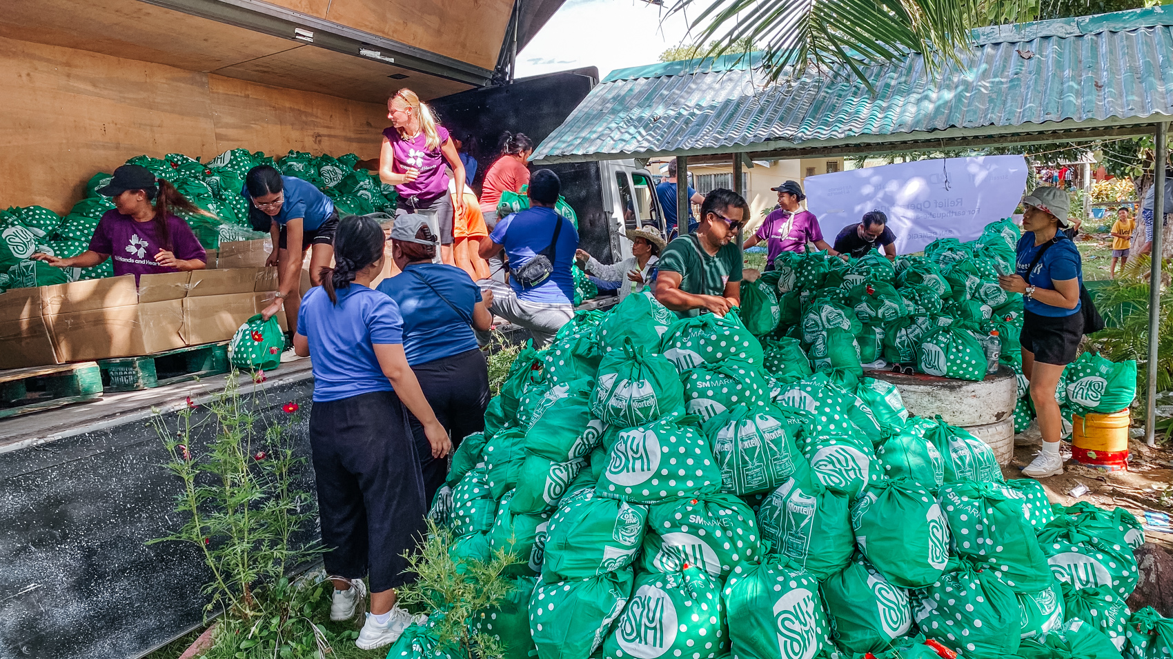 Dos voluntarios All Hands and Hearts organizan alimentos enlatados en un centro de distribución.