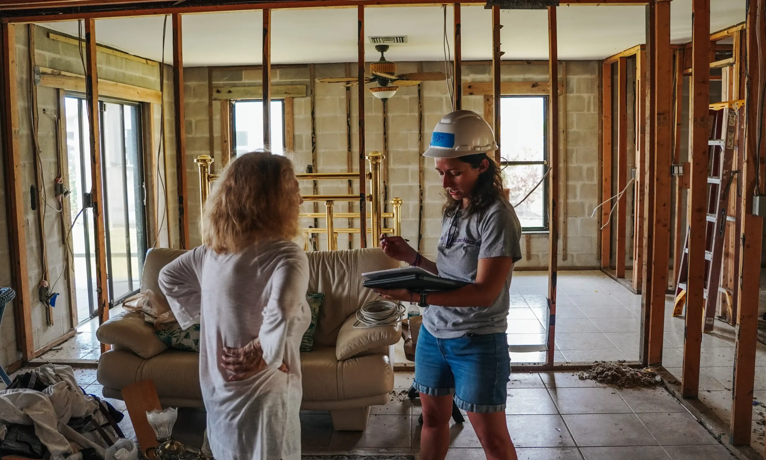 An All Hands and Hearts staff member speaks with a homeowner inside her home, which is fully gutted