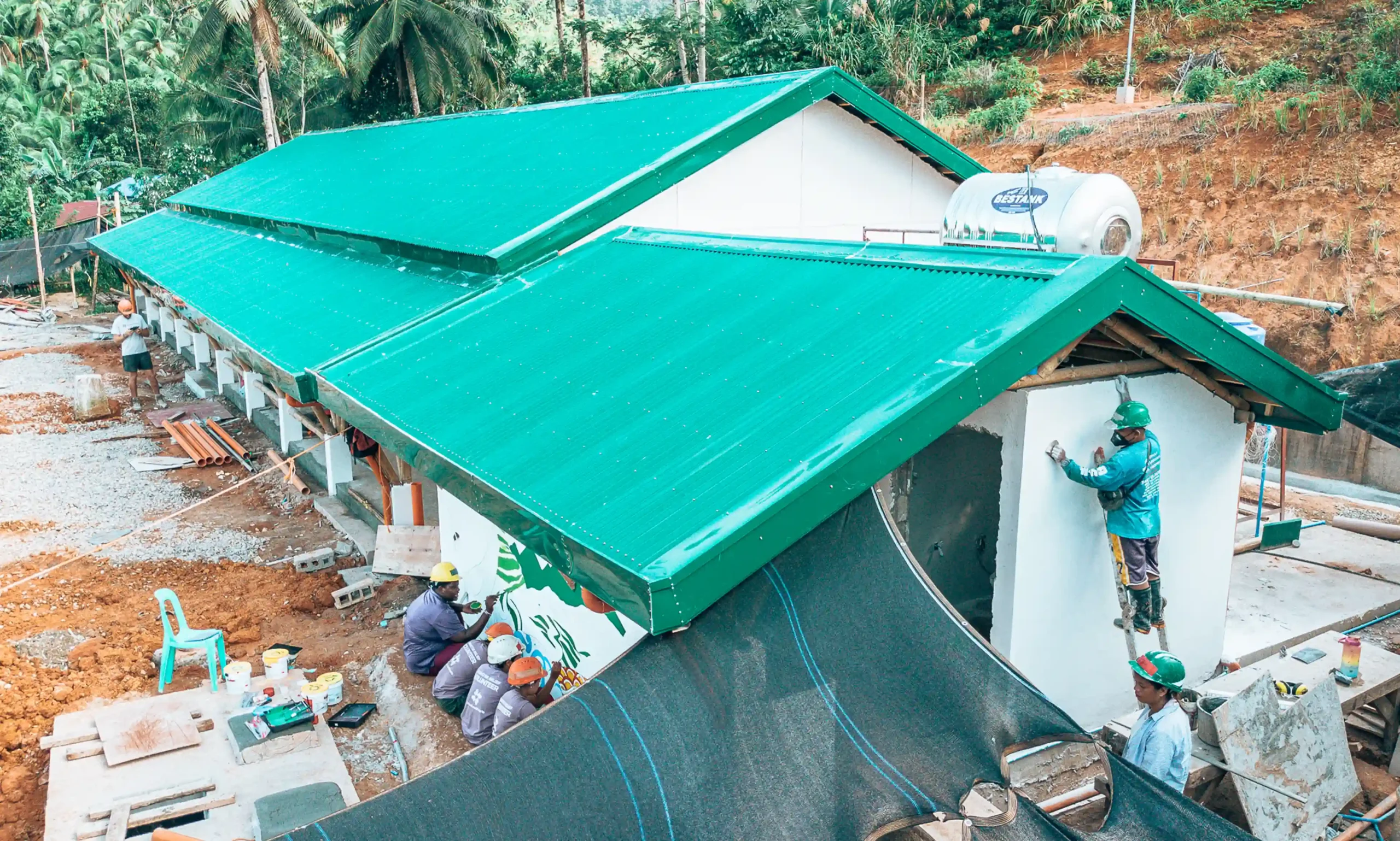 Una escuela recién construida. El personal y los voluntarios All Hands and Hearts pintan las paredes exteriores.
