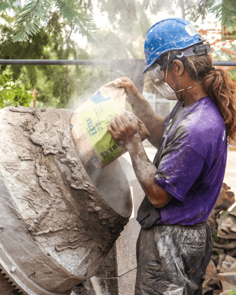 Volunteering pouring cement into a mixer