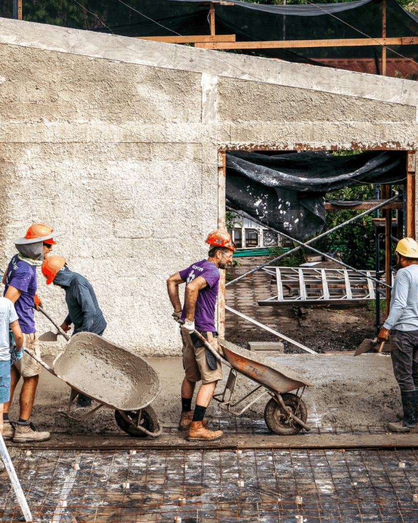 Volunteers holding wheel barrels, pouring cement