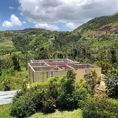 Storm-damaged home in Puerto Rico showing only its concrete walls left standing after a hurricane.