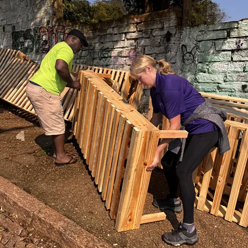 A volunteer and community member move a bed