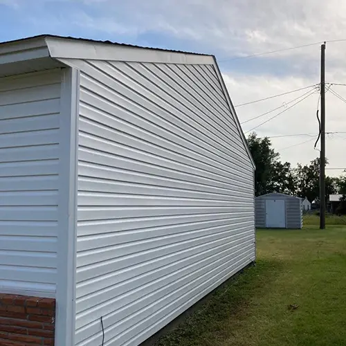 The side of a house with brand-new white siding after tornado repairs.