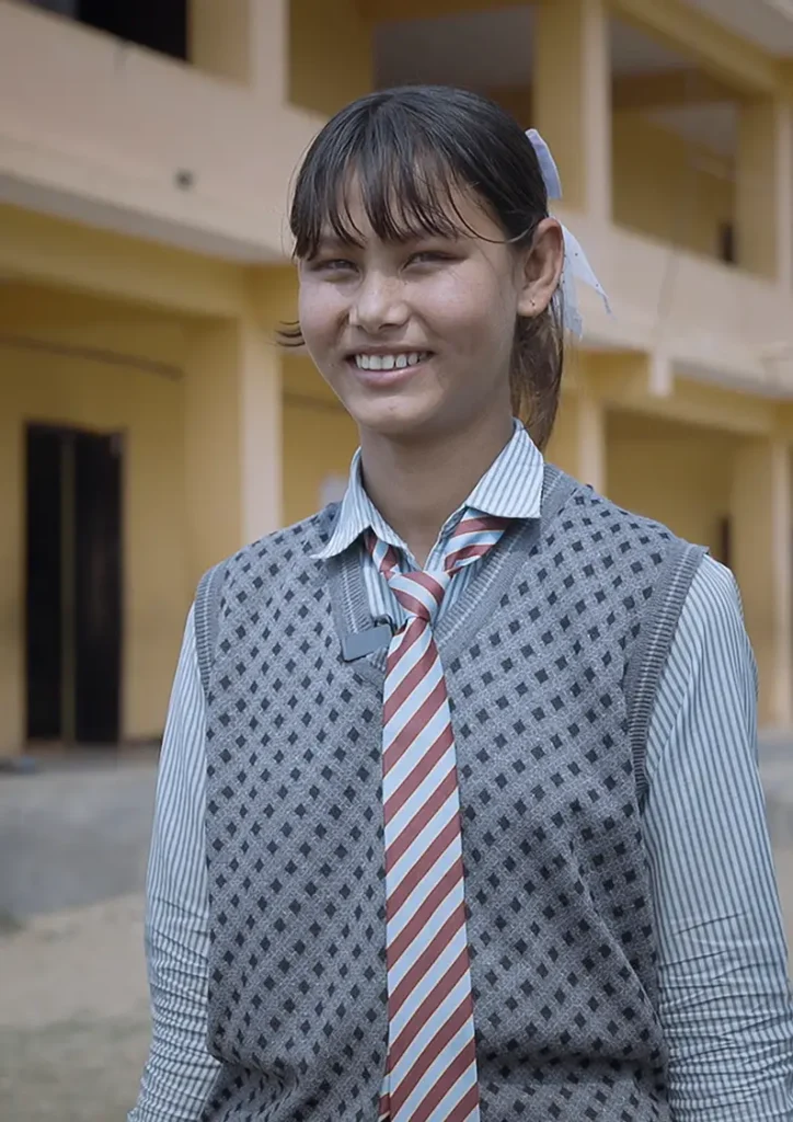 Smritri, a student in Makwanpur, Nepal. smiles at the camera in her school uniform