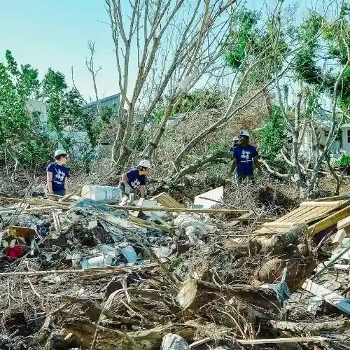 Florida Keys hurricane relief volunteers clearing piles of debris and fallen trees after storm damage.
