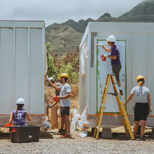 Maui wildfire relief volunteers painting walls of temporary housing structures during recovery work.