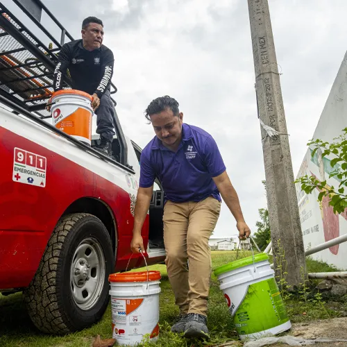 Team members carrying buckets of supplies from a truck to support hurricane recovery.