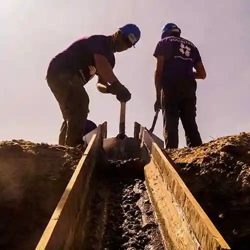 Voluntarios palean cemento húmedo en marcos de madera como parte de los esfuerzos de reconstrucción en Perú.
