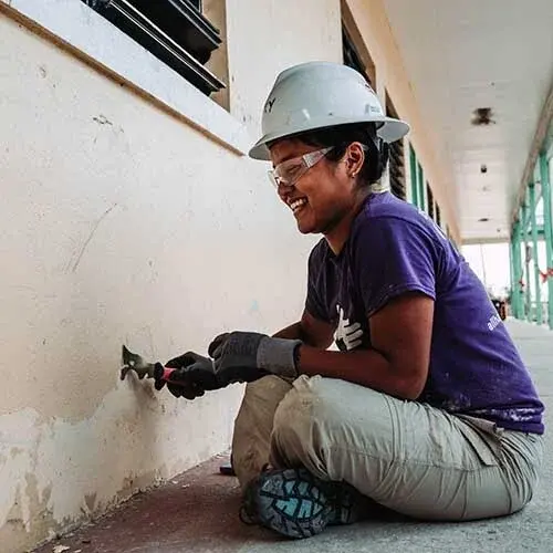 A volunteer scraping a wall