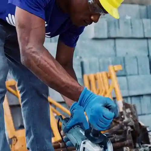 Volunteer in safety gear using a power tool to cut construction materials during Puerto Rico hurricane recovery.