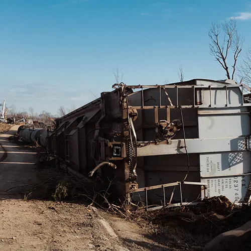 Overturned rail car lying on its side along a road after Kentucky tornado damage.