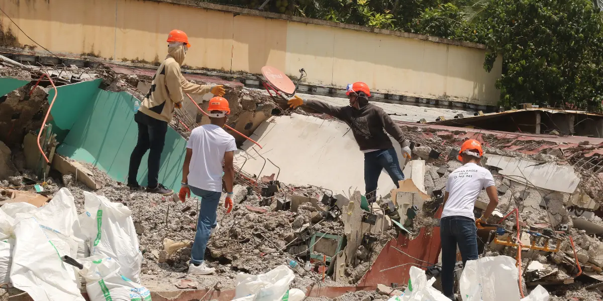 Four individuals removing rubble from collapsed building