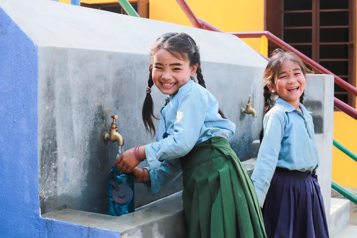 Two young female students washing hands at new handing washing station
