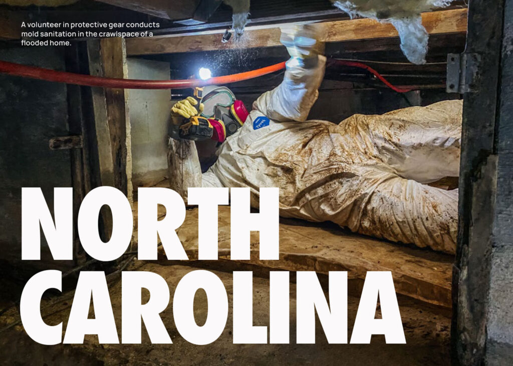 A volunteer in protective gear conducts mold sanitation in the crawlspace of a flooded home.