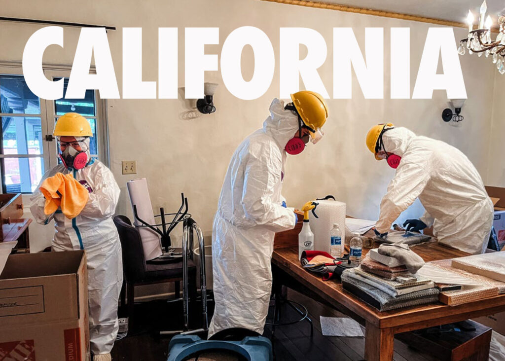 3 volunteers in protective gear carefully cleans and packs a homeowner's belongings